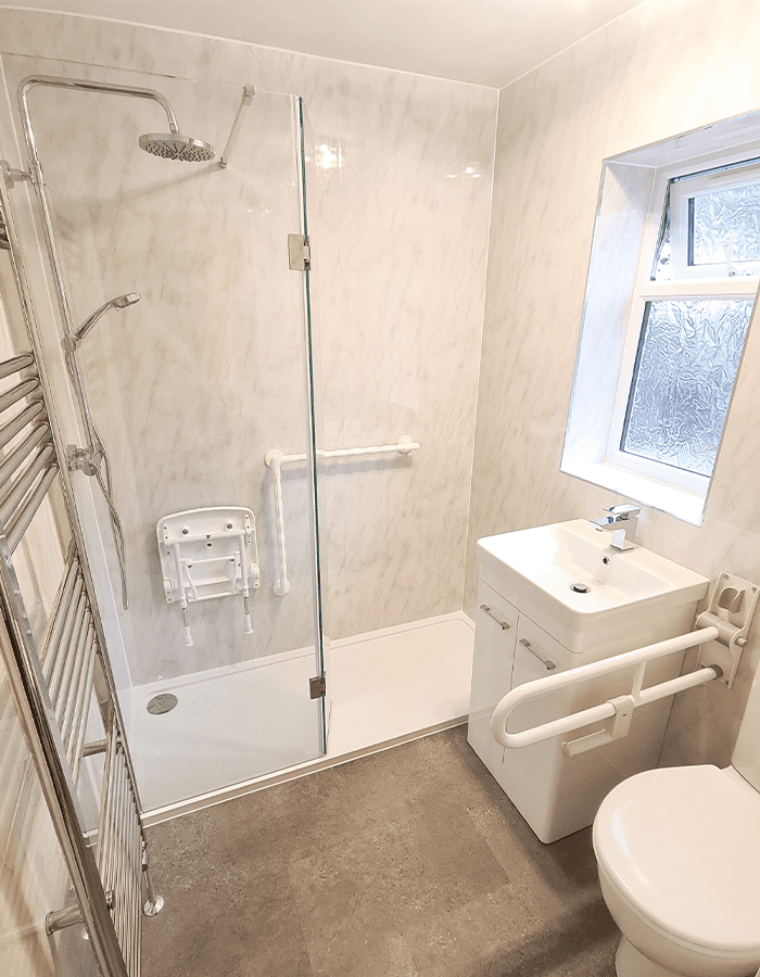 Disabled shower room with shower seat, shower railing and toilet barrier fitted by Aqaurella Bathrooms